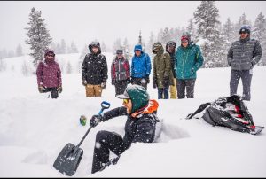 A CBAC professional uses a shovel to demonstrate strong/weak layers in the snowpack.