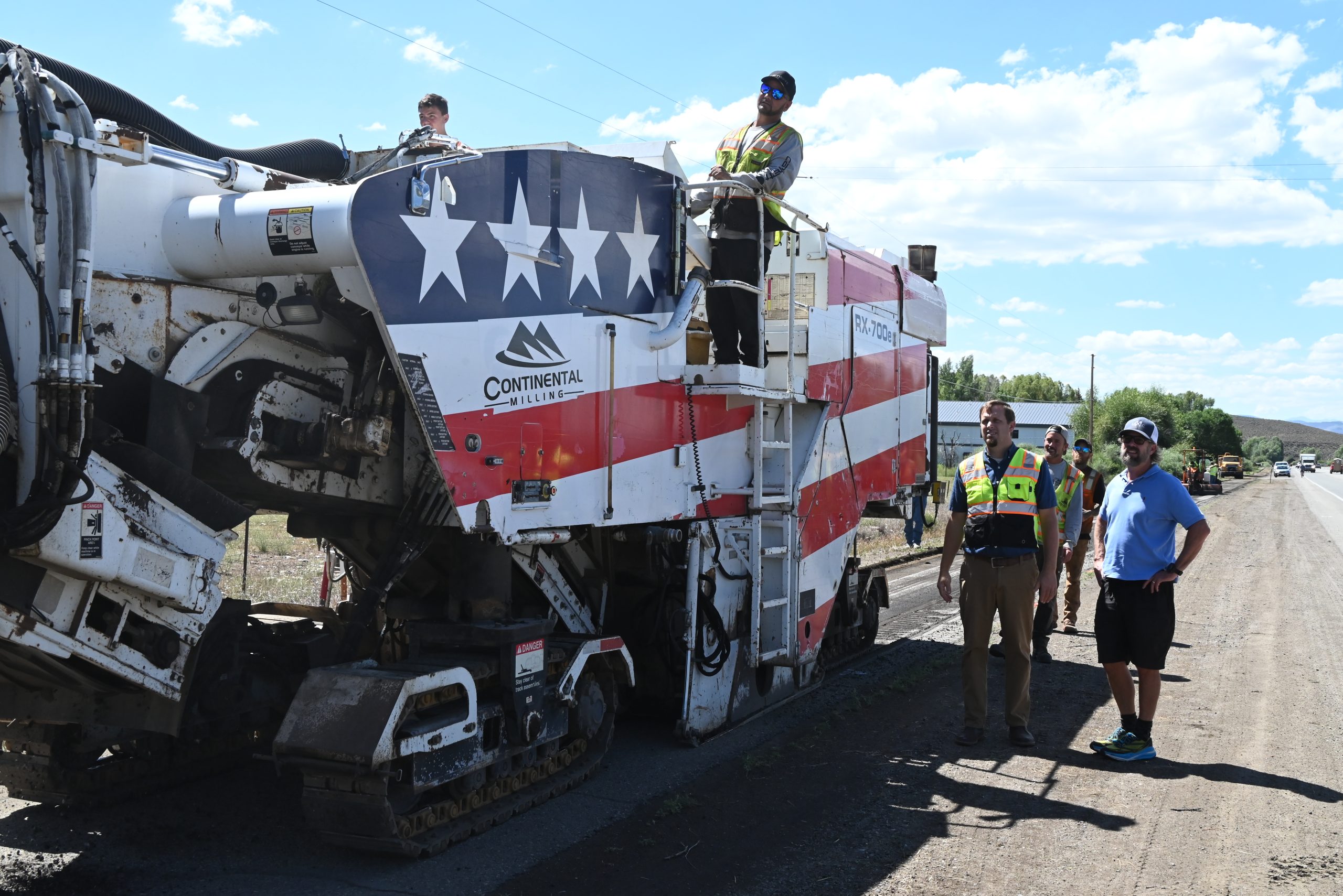 Workers run a machine resurfacing asphalt
